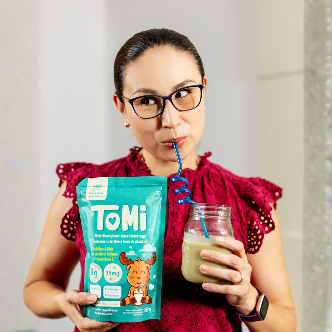 Founder drinking a smoothie from a glass while holding a TOMi package.
